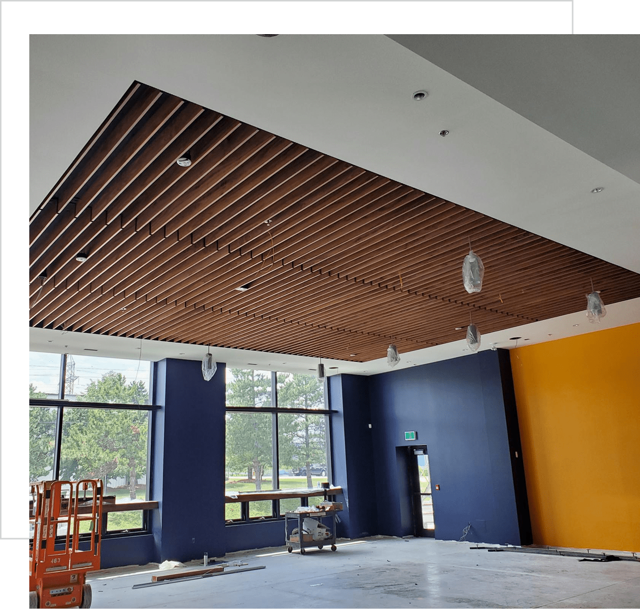 Modern room with wooden ceiling and windows.