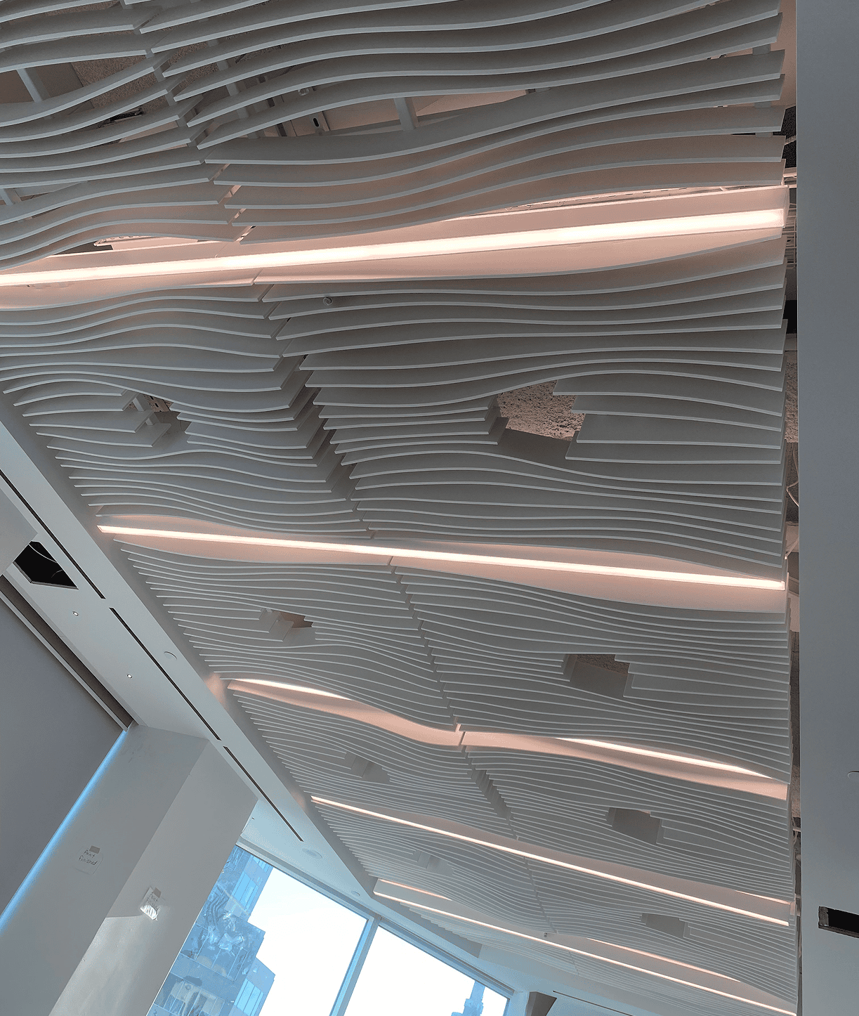 Wavy slatted ceiling with linear LED lights