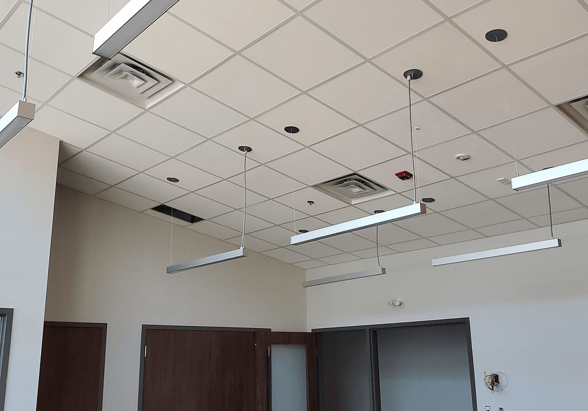 Office ceiling with hanging lights and panels.