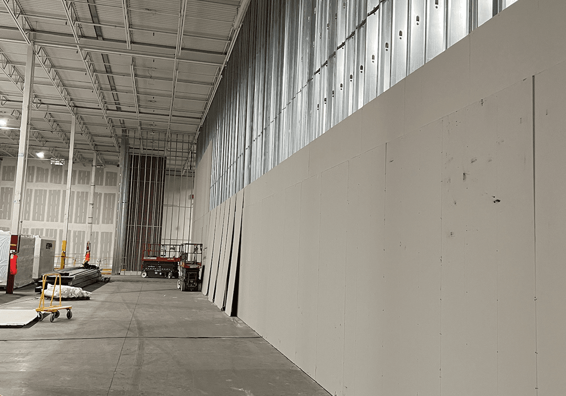 Warehouse interior with unfinished drywall installation.